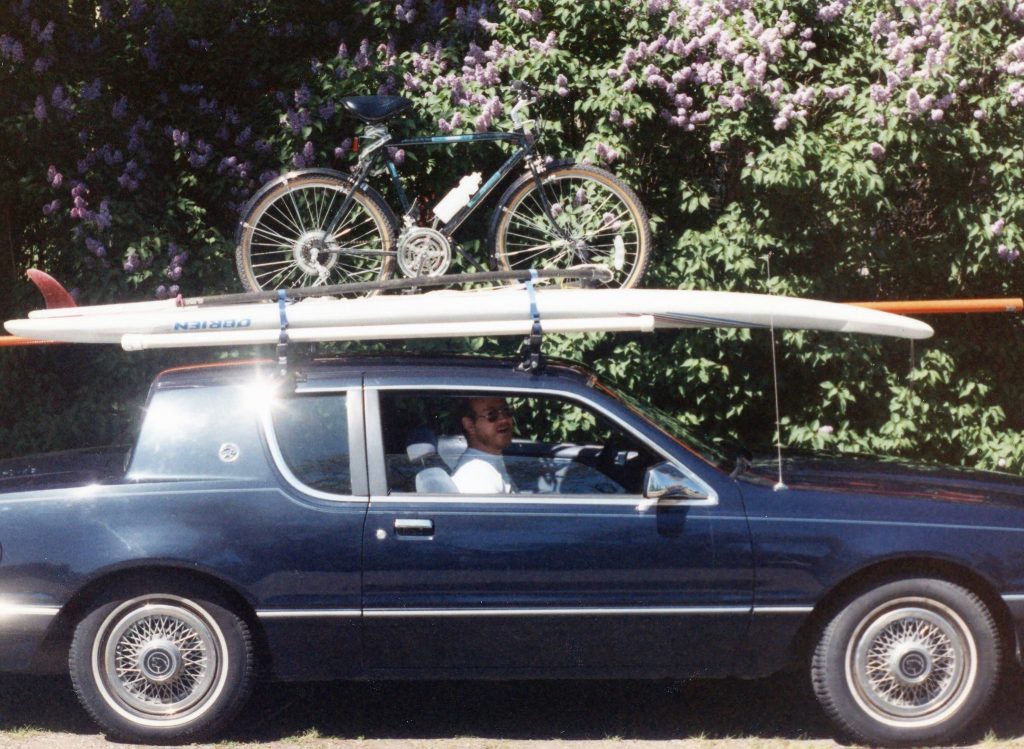 My midnight blue 1986 Mercury Cougar with a sail board and bike on top.